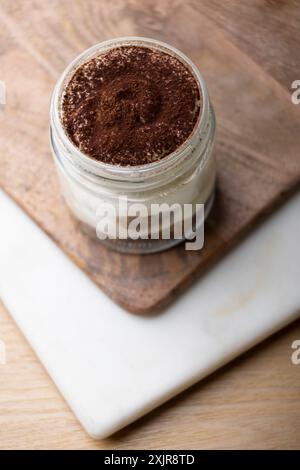 Köstliches Tiramisu-Dessert in einem Glasgefäß mit cremigen Schichten Mascarponenkäse und in Kaffee getränkten Marienfinger. Stockfoto