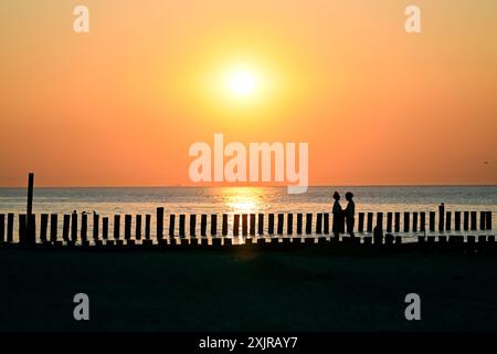 Reise - Wangerooge 2024 Uhr 19.07.2024 Strand von Wangerooge beim Sonnenuntergang. Ein verliebtes Paar steht sich beim Sonnenuntergang gegenüber. Foto: Osnapix Reisen - Wangerooge 2024 *** Reise Wangerooge 2024 am 19 07 2024 Strand von Wangerooge bei Sonnenuntergang Ein verliebtes Paar, das sich bei Sonnenuntergang gegenübersieht Foto osnapix Travel Wangerooge 2024 MT Stockfoto