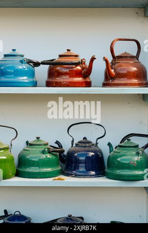 Sammlung von farbenfrohen Vintage-Teekannen auf weißen Regalen, mit einer Vielzahl von Designs und lebhaften Farben. Stockfoto