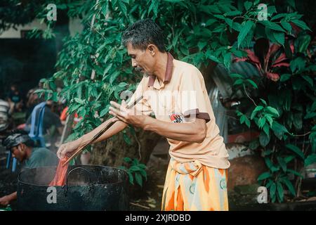 Ein balinesischer Mann in einem Sarong bereitet Essen vor einer Zeremonie in Bali, Indonesien, am 9. Januar 2015 zu Stockfoto