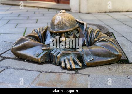 Bratislava, Slowakei – 25. Mai 2024: Cumil man at Work Bronzeskulptur mit Blick auf eine Gully-Hülle, die 1997 von Viktor Hulik hergestellt wurde Stockfoto