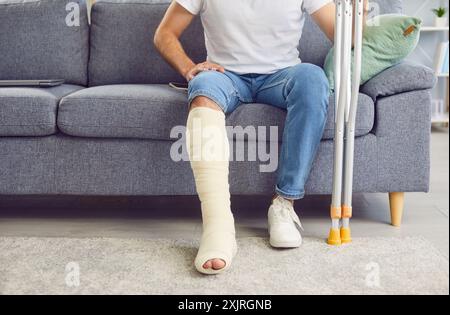 Ein Mann mit gebrochenem Bein sitzt auf dem Sofa, Nahaufnahme Stockfoto