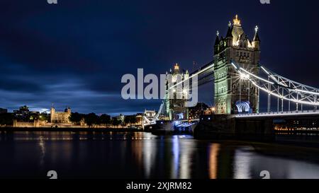 Tower Bridge, die die Themse überspannt, nachts beleuchtet, mit dem Tower of London daneben Stockfoto