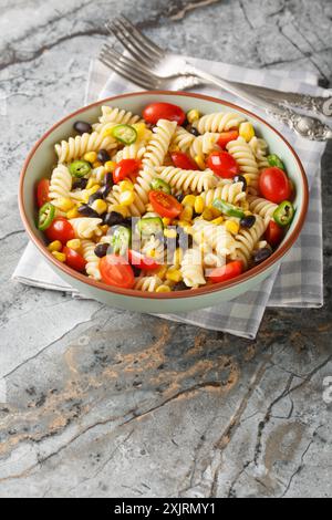 Vegetarischer mexikanischer Makkaroni-Nudelsalat mit schwarzen Bohnen, Mais, Tomaten, Zwiebeln und Jalapeno in Nahaufnahme auf einem Teller auf dem Tisch. Vertikal Stockfoto
