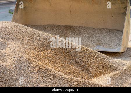 Der Baggerlöffel nimmt zerquetschten Stein für Straßenreparaturen auf. Stockfoto