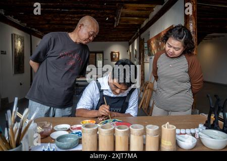 Kunming, chinesische Provinz Yunnan. Juli 2024. Chen Jianming (L) aus Chongqing und seine Frau beobachten ein Gemälde mit Mineralpigmenten im Dorf Tuguachong im Bezirk Malong der Stadt Qujing, südwestchinesische Provinz Yunnan, 10. Juli 2024. Quelle: Hu Chao/Xinhua/Alamy Live News Stockfoto