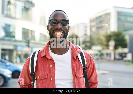 Glücklicher junger afrikanischer Schwarzer, der auf der Straße steht und in die Kamera schaut. Hochformat Stockfoto