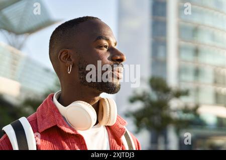 Junger afrikanischer Mann, der auf der Stadtstraße steht und träumend wegschaut. Nahaufnahme. Stockfoto