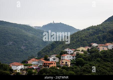 Blick auf das Dorf Rabac an der istrischen Küste Kroatiens mit den Bergen und der Altstadt von Labin im Hintergrund Stockfoto