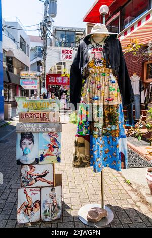 Schild und Kleid werden auf einem Stand draußen auf dem Bürgersteig beim beliebten Second Hand Store (nicht abgebildet) Panama Boy in der Takeshita Street, Harajuku ausgestellt. Stockfoto