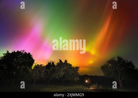 Spaziergang mit einer Laterne unter faszinierenden Nordlichtern über Mitteleuropa. Leuchtende Aurora Borealis in Pink, Grün, Orange und Gelb. Stockfoto