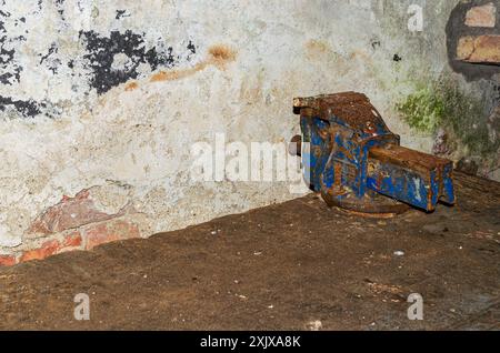 Der alte, verrostete Eisenbankschrauber sitzt auf einer alten Werkbank Stockfoto