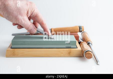 Mann, Frau, Handwerker, der die Schräge einer Meißelklinge auf einem Schleifstein schärft Stockfoto