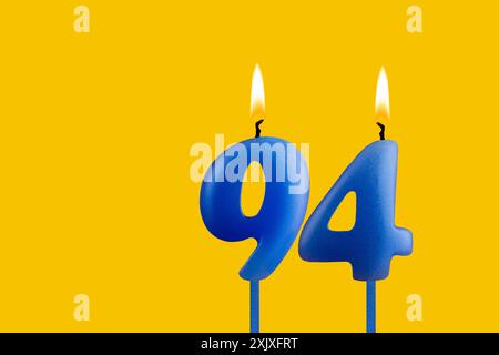 Blaue Kerze Nummer 94 - Geburtstag auf gelbem Hintergrund Stockfoto