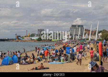 Southend auf See, Großbritannien. Juli 2024. Ein lebhafter Sommertag in Southend-on-Sea, Essex, bei dem Strandbesucher die Küste genießen. Familien und Einzelpersonen entspannen sich unter Sonnenschirmen und Zelten, während andere am Ufer spazieren oder schwimmen. Die Kulisse umfasst moderne Gebäude und Fahrgeschäfte in den Vergnügungsparks, die die lebhafte Küstenatmosphäre der Stadt einfangen. Temperaturen bei 22 Grad kurz nach Mittag machen sich viele Leute auf den Weg zum Strand, um die Sonne am frühen Nachmittag zu genießen. Penelope Barritt/Alamy Live News Stockfoto