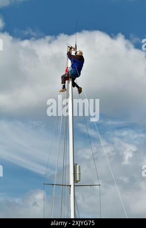 Matrose, Segler in Einem Bosuns Stuhl, der ein Anenometer auf Einem Stahlmast Einer Yacht repariert, Segelboot, Großbritannien Stockfoto