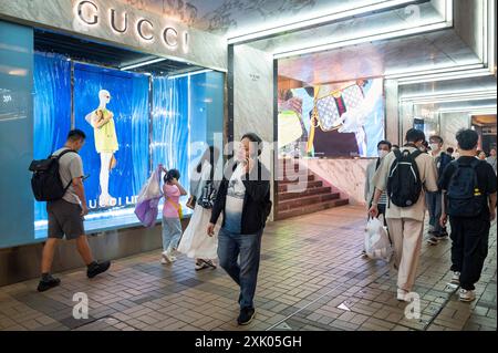Shopper laufen am italienischen Luxusmodemarke Gucci-Logo vorbei und laden in Hongkong ein. Stockfoto