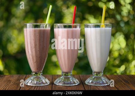 Set aus verschiedenen köstlichen Milchshakes oder Smoothies in Gläsern mit Stroh auf dem Tisch im Freien Stockfoto