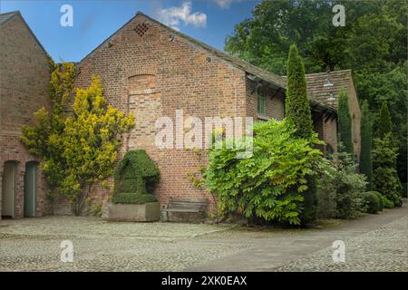 Blick über einen gepflasterten Hof auf ein Gebäude und das Giebelende eines Hauses Stockfoto