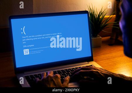 Mann mit Laptop, der auf dem Monitor Blue Screen of Death oder BSOD zeigt. Fehlerhaftes Microsoft-Betriebssystem Windows 10. Stockfoto