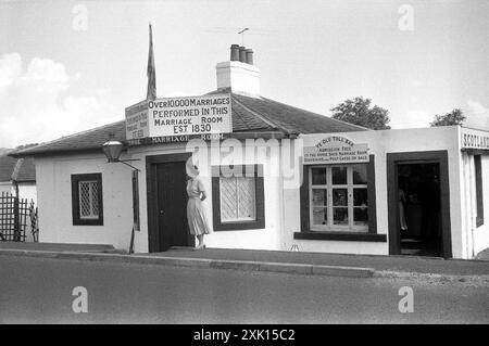 Gretna Green, Schottland. 1957: „YE Old toll Bar“ & „Horse Shoe Marriage Room“ an der B7076 in Gretna, Dumfries und Galloway. Das Haus wurde 1830 als „First House in Scotland“ erbaut. Auf dem Schild über der Tür steht „über 10.000 Ehen in diesem Heiratsraum“. Im angeschlossenen Souvenirladen wurden Souvenirs und Postkarten verkauft. Stockfoto