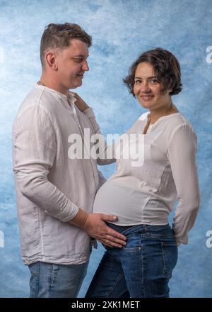 Junge schwangere Frau mit ihrem Mann. Der Mann umarmt den Bauch der schwangeren Frau zärtlich Stockfoto