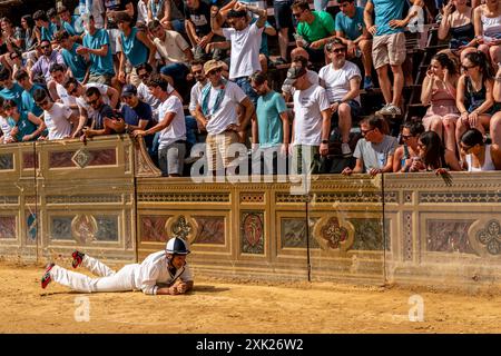 Am ersten Tag des Palio liegt Ein Jockey auf der Strecke, nachdem er sein Pferd während eines der „Batterien“ (Trials) des Palio, Siena, Italien, verlassen hat. Stockfoto