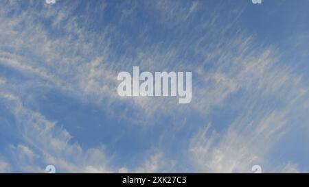 Weitläufiger blauer Himmel mit zarten weißen Wolken, die eine ruhige und offene Atmosphäre schaffen. Stockfoto