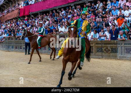 Jockeys in ihren Contrada-Farben machen sich auf den Weg zur Startlinie für das Palio-Rennen. Das Rennen dauert weniger als 90 Sekunden in Siena, Toskana, Italien. Stockfoto