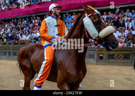 Jockeys in ihren Contrada-Farben machen sich auf den Weg zur Startlinie für das Palio-Rennen. Das Rennen dauert weniger als 90 Sekunden in Siena, Toskana, Italien. Stockfoto