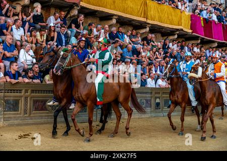 Jockeys in ihren Contrada-Farben machen sich auf den Weg zur Startlinie für das Palio-Rennen. Das Rennen dauert weniger als 90 Sekunden in Siena, Toskana, Italien. Stockfoto