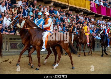 Jockeys in ihren Contrada-Farben machen sich auf den Weg zur Startlinie für das Palio-Rennen. Das Rennen dauert weniger als 90 Sekunden in Siena, Toskana, Italien. Stockfoto