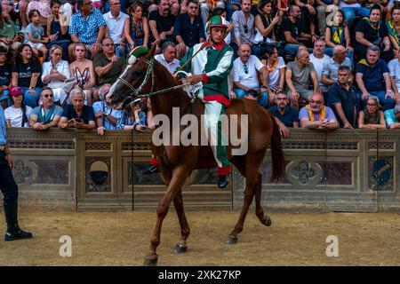 Jockeys in ihren Contrada-Farben machen sich auf den Weg zur Startlinie für das Palio-Rennen. Das Rennen dauert weniger als 90 Sekunden in Siena, Toskana, Italien. Stockfoto