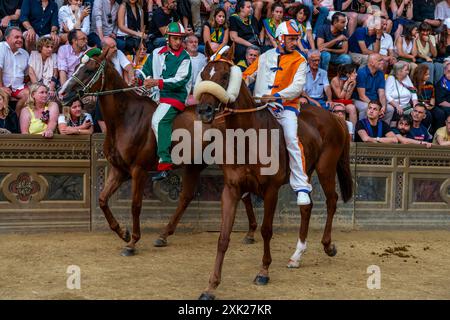 Jockeys in ihren Contrada-Farben machen sich auf den Weg zur Startlinie für das Palio-Rennen. Das Rennen dauert weniger als 90 Sekunden in Siena, Toskana, Italien. Stockfoto