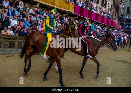 Jockeys in ihren Contrada-Farben machen sich auf den Weg zur Startlinie für das Palio-Rennen. Das Rennen dauert weniger als 90 Sekunden in Siena, Toskana, Italien. Stockfoto