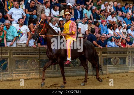 Jockeys in ihren Contrada-Farben machen sich auf den Weg zur Startlinie für das Palio-Rennen. Das Rennen dauert weniger als 90 Sekunden in Siena, Toskana, Italien. Stockfoto