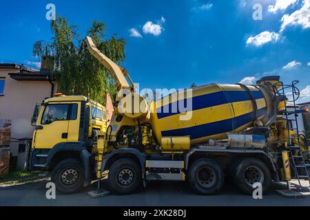 Ein großer schwarz-gelber Betonmischer mischt und gießt Beton, während die Fundamente eines Hauses gebaut werden Stockfoto