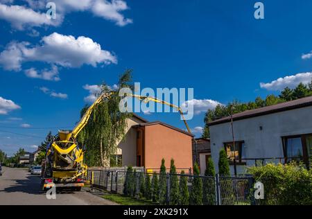 Ein großer schwarz-gelber Betonmischer mischt und gießt Beton, während die Fundamente eines Hauses gebaut werden Stockfoto