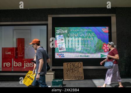 Madrid, Spanien. Juli 2024. Während der ersten Hitzewelle, unter der die spanische Hauptstadt leidet, laufen die Menschen vor einem Schild eines Obdachlosen, auf dem steht: „Ich bin hungrig, ich akzeptiere alle Arten von Hilfe“ im Zentrum von Madrid. (Credit Image: © David Canales/SOPA Images via ZUMA Press Wire) NUR REDAKTIONELLE VERWENDUNG! Nicht für kommerzielle ZWECKE! Stockfoto