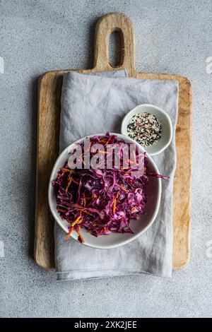 Köstliches und nahrhaftes Mittagessen mit frischem Rotkohl- und Karottensalat, begleitet von gekochtem Bulgur, serviert auf einem rustikalen Holzbrett Stockfoto