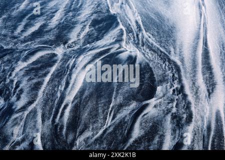 Entdecken Sie die fesselnden abstrakten Muster, die von schwarz-weißem Sand an den unberührten Ufern der Lofoten gebildet werden, wodurch eine atemberaubende natürliche Artwo entsteht Stockfoto