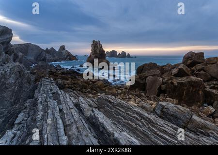 Ein atemberaubender Blick auf die Costa Quebrada in Kantabrien mit felsigen Küsten und dramatischen Felsformationen vor einem Dämmerungshimmel Stockfoto