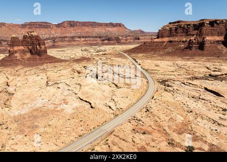 Ein malerischer Blick auf eine lange, kurvenreiche Straße, die durch das trockene, strukturierte Gelände des White Canyon führt, das sich in der Glen Canyon National Recreation Area befindet. Stockfoto
