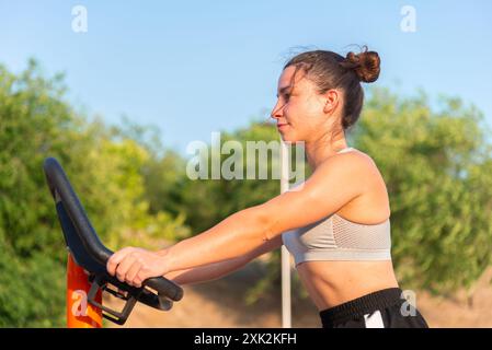 Die junge Frau arbeitet an einem sonnigen Tag mit Fitnessgeräten an und demonstriert dabei Konzentration und Anstrengung bei ihrer Übung Stockfoto