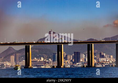 Rio-Niteroi-Brücke an der Guanabara-Bucht - dichte Luftverschmutzung über der Innenstadt von Rio de Janeiro - Christusstatue und Corcovado-Berg im Hintergrund. Rio de Janeiro, Brasilien. Stockfoto