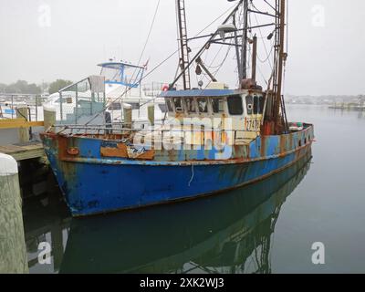 Altes verrosttes blaues Boot am Dock mit etwas Nebel im Hyannis Hafen, am Cape Cod Massachusetts, USA. Stockfoto