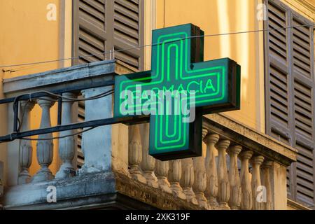 FARMACIA – ein grünes Neonapothekenkreuz – ein Schild über einer Apotheke in Italien. Stockfoto