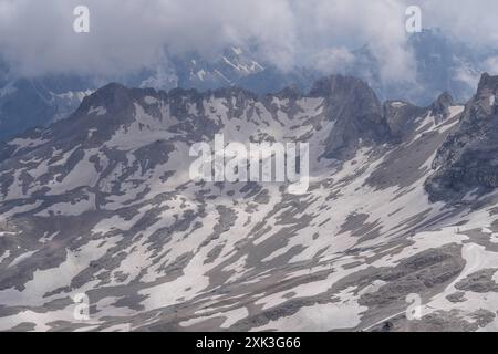 Symbolbild Wanderer, felsiges Gelände, Berglandschaft, steiler Aufstieg, Rucksack, schneebedeckte Flecken, Wanderroute, Gebirgspfad, Outdoor-Aktivität, Bergwandern, Menschen in der Ferne, karge Landschaft, steiniger Pfad, hochgelegene Region, Geröllfeld, Panorama, Berggipfel, Wolkenhimmel, Bergblick, Alpines Klima, kühle Temperaturen, dünne Luft, Klimawandel, schmelzende Gletscher, veränderte Wetterbedingungen, Zugspitze, Alpen, imposante Bergformationen, Seilbahn *** symbolischer Imagewanderer, felsiges Gelände, Berglandschaft, steiler Aufstieg, Rucksack, schneebedeckte Flecken, Wanderroute, Bergwelt Stockfoto