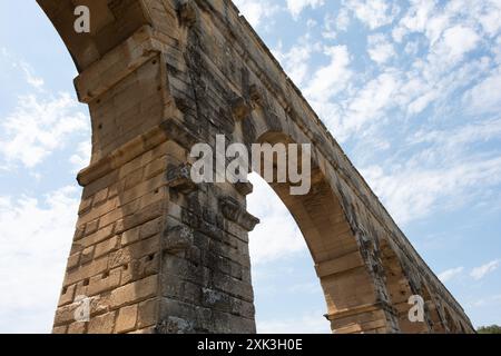 VERS-PONT-DU-GARD, Frankreich – der majestätische Pont du Gard, ein altes römisches Aquädukt und UNESCO-Weltkulturerbe, erstreckt sich über den ruhigen Fluss Gardon in Südfrankreich. Diese bemerkenswerte dreistöckige Brücke zeigt den Einfallsreichtum römischer Technik vor dem Hintergrund der malerischen mediterranen Landschaft. Stockfoto