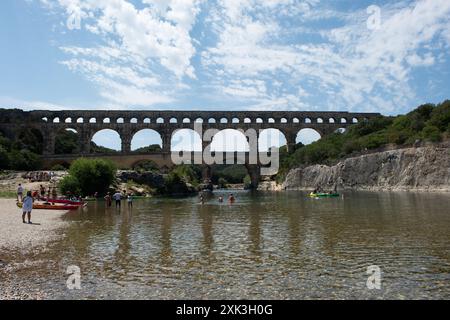 VERS-PONT-DU-GARD, Frankreich – der majestätische Pont du Gard, ein altes römisches Aquädukt und UNESCO-Weltkulturerbe, erstreckt sich über den ruhigen Fluss Gardon in Südfrankreich. Diese bemerkenswerte dreistöckige Brücke zeigt den Einfallsreichtum römischer Technik vor dem Hintergrund der malerischen mediterranen Landschaft. Stockfoto